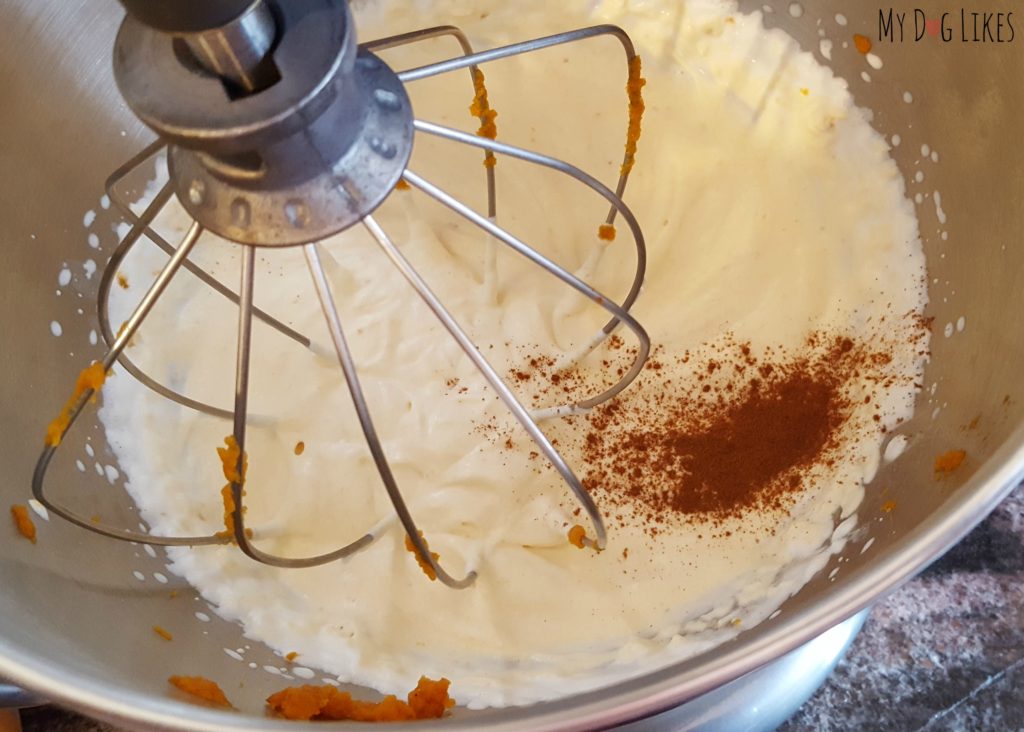 Adding cinnamon to the cream and pumpkin mixture in the bowl